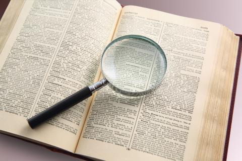 Open dictionary with magnifying glass