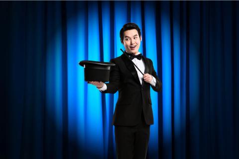 Performer gestures in front of a theater curtain